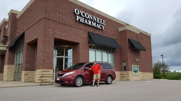 The O'Connell Pharmacy storefront with the delivery car parked out front