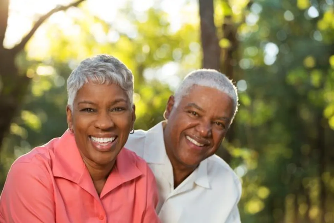 A smiling couple outdoors in warm sunlight